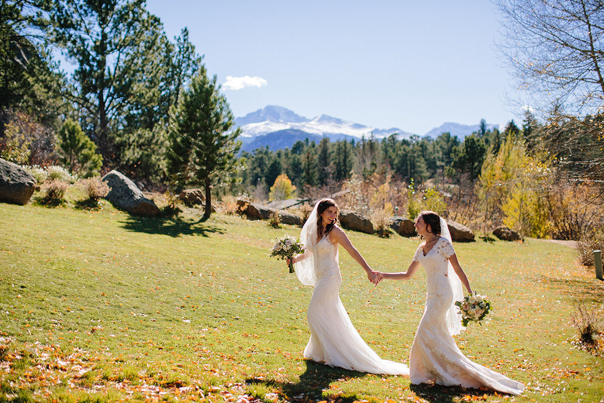 Rustic mountain wedding in the Colorado Rocky Mountains two brides lace white dresses veils running