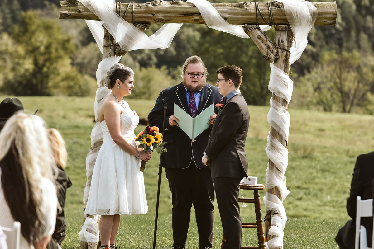 This moody fall ranch wedding in the Blue Ridge Mountains is a dream two brides lesbian wedding colorful boots roller derby skates purple bow tie dark tux white tea length dress crystal necklace rainbow vows