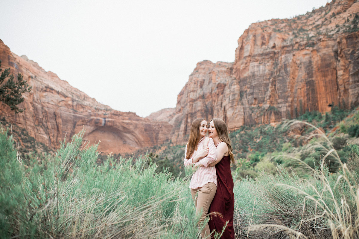 Utah mountains are the backdrop for this Zion National Park engagement lesbian long maroon dress pink pinstriped shirt mountains cliffs