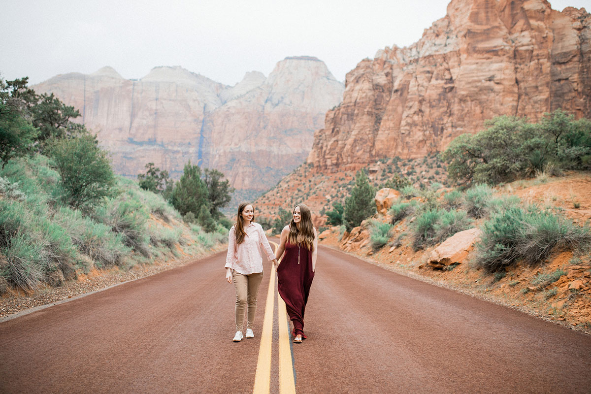 Utah mountains are the backdrop for this Zion National Park engagement lesbian long maroon dress pink pinstriped shirt mountains cliffs