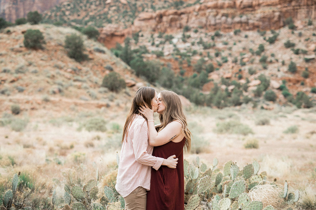 Utah mountains are the backdrop for this Zion National Park engagement lesbian long maroon dress pink pinstriped shirt mountains cliffs kiss
