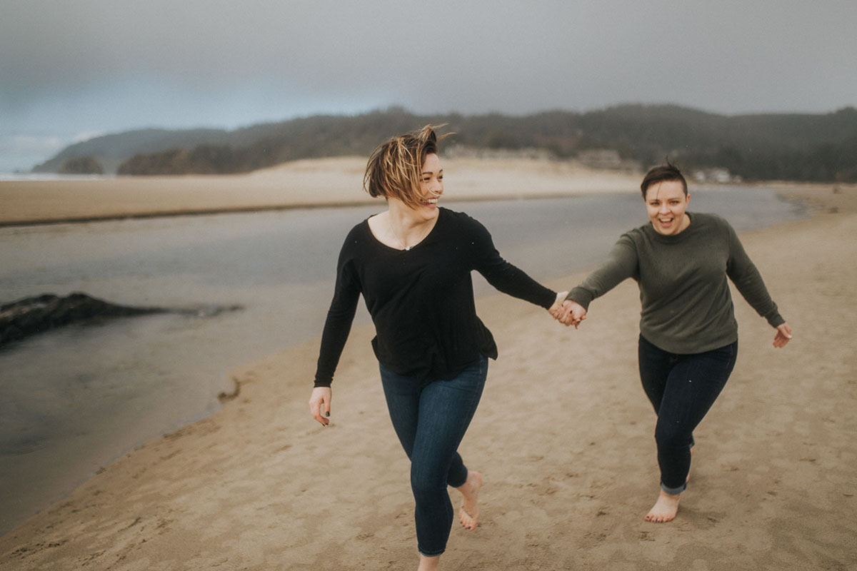 Romantic beach engagement photos on the Oregon Coast two brides Cannon Beach waterfront oceanside running