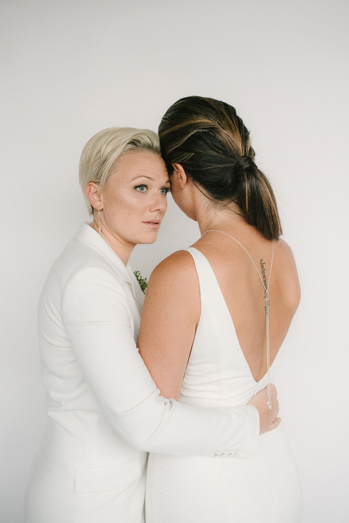 Crisp white modern wedding inspiration in Nashville, Tennessee two brides pantsuit dress candles natural greenery
