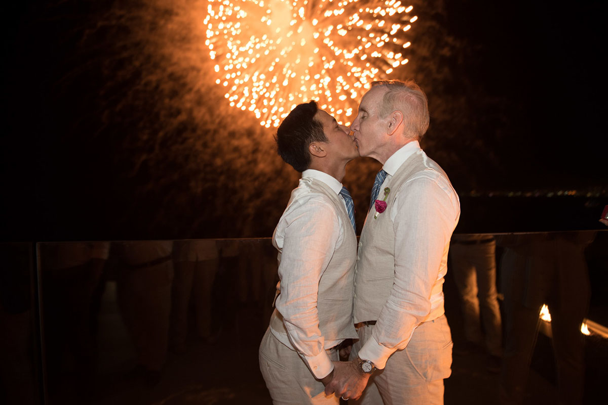 Tropical destination white beach wedding in Puerto Vallarta, Mexico two grooms linen tailored suits tradition whimsical kiss fireworks