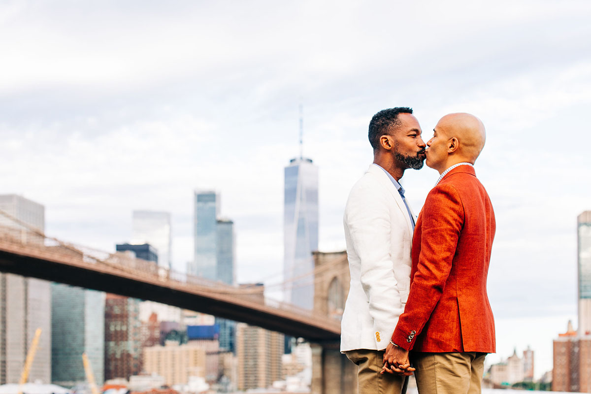 Colorful red and white engagement photos in Brooklyn, New York red suit two grooms husbands Brooklyn Bridge New York City kiss