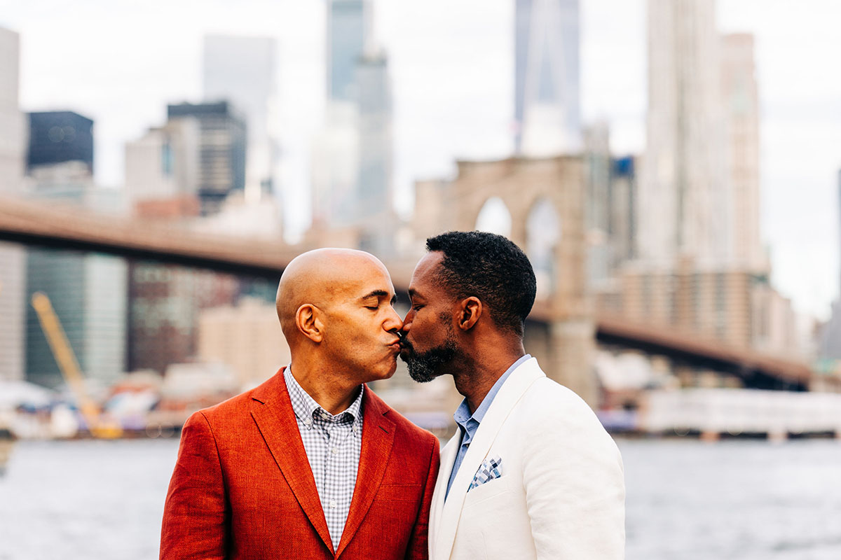 Colorful red and white engagement photos in Brooklyn, New York red suit two grooms husbands Brooklyn Bridge New York City