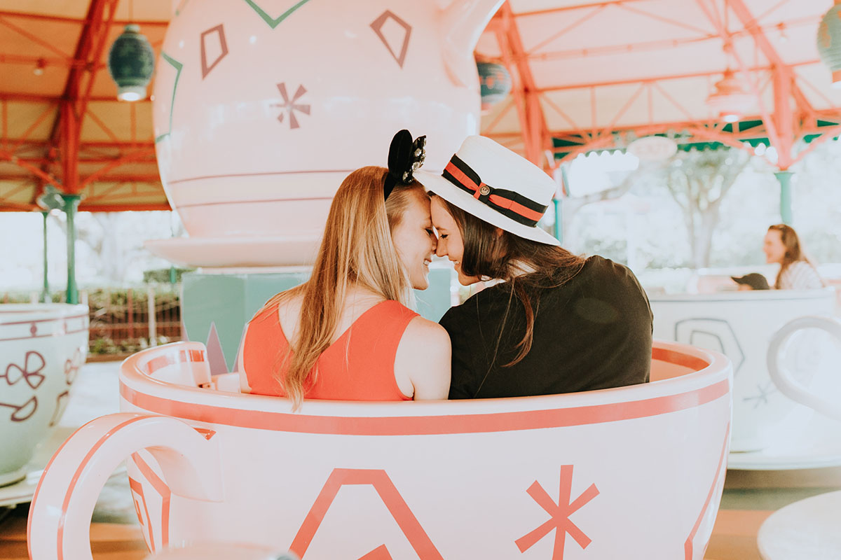 Fun, colorful engagement photos at Walt Disney World colorful red mouse ears coordinated outfits two brides same-sex lesbian engagement teacups