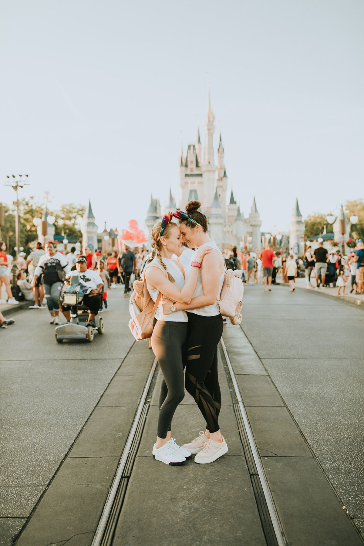 Fun, colorful engagement photos at Walt Disney World colorful red mouse ears coordinated outfits two brides same-sex lesbian engagement