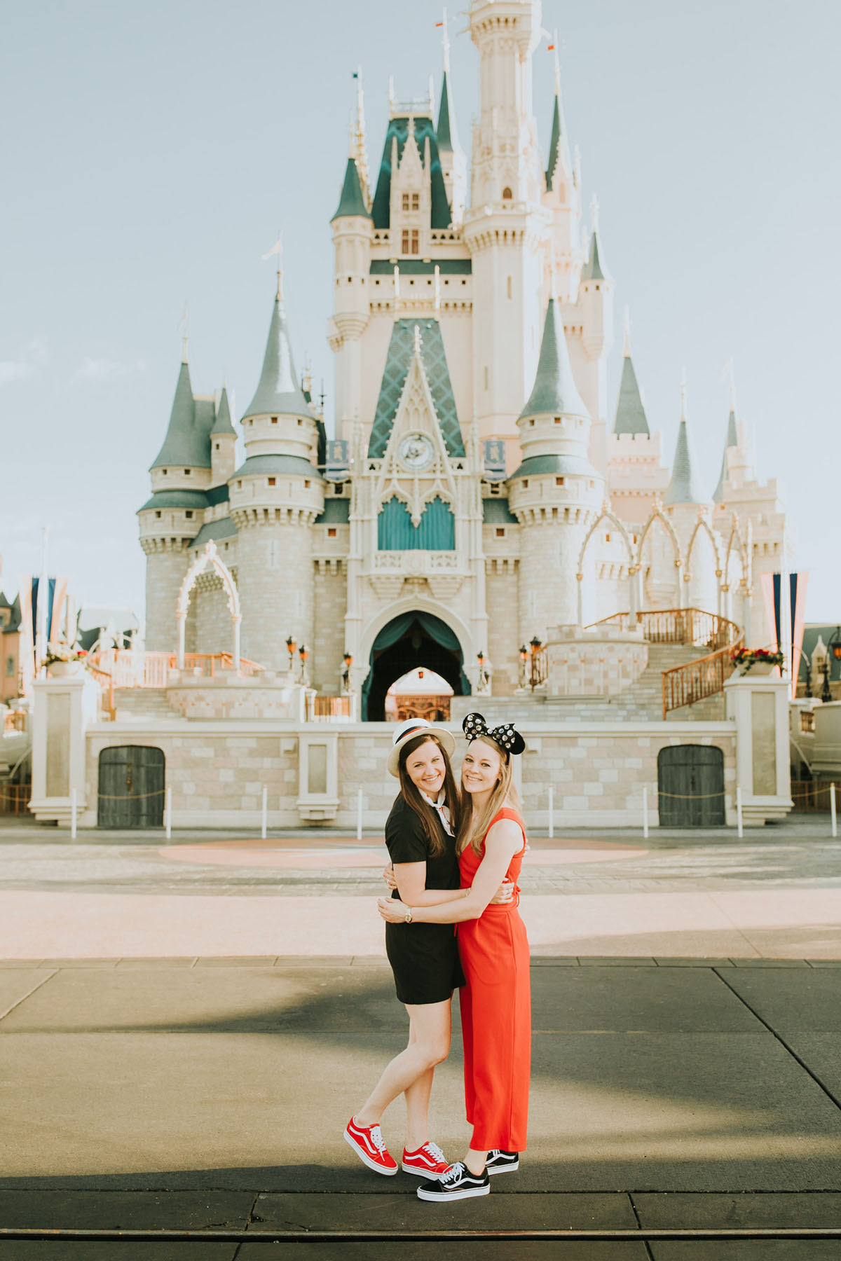 Fun, colorful engagement photos at Walt Disney World colorful red mouse ears coordinated outfits two brides same-sex lesbian engagement cinerella castle