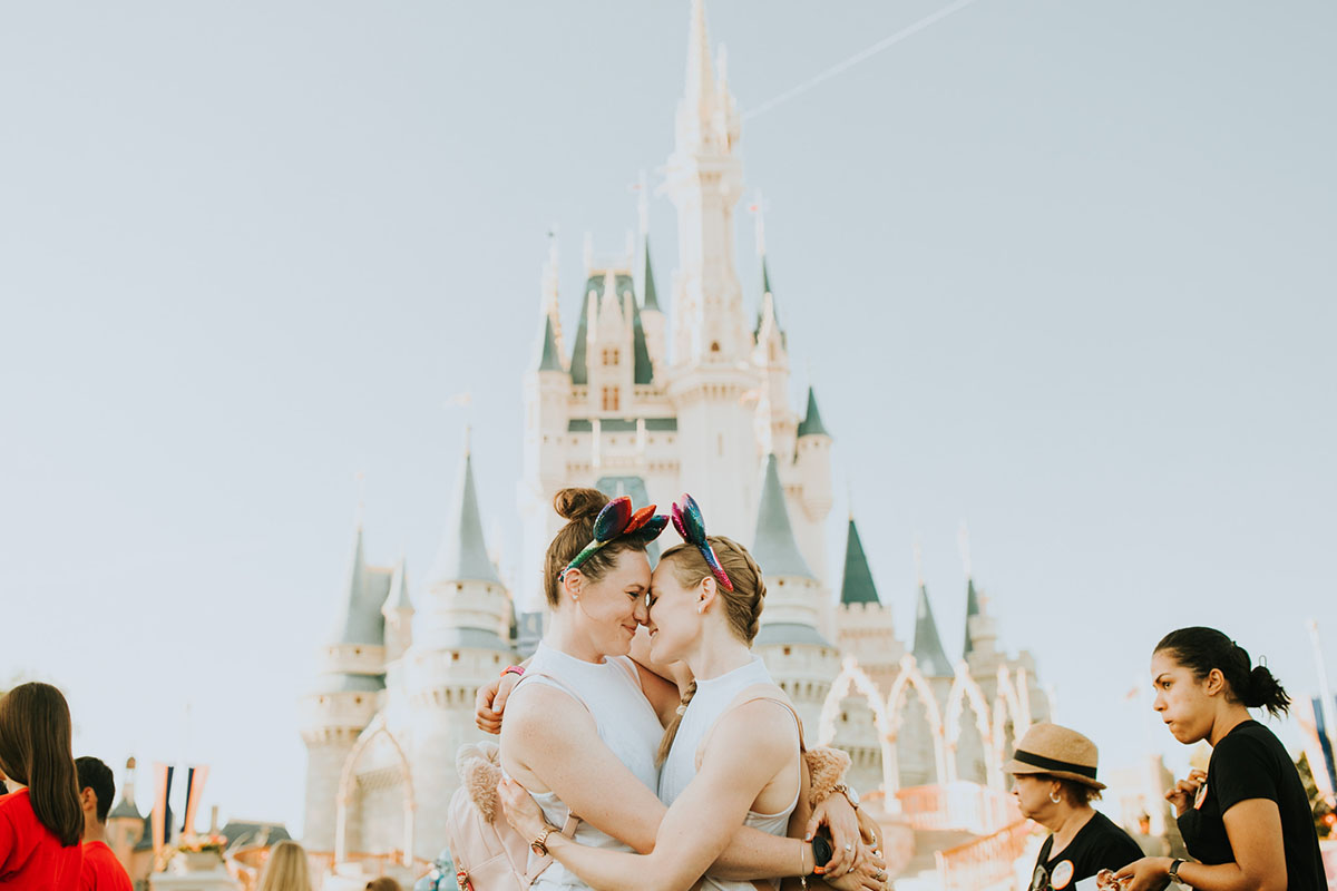 Fun, colorful engagement photos at Walt Disney World colorful red mouse ears coordinated outfits two brides same-sex lesbian engagement cinderella castle