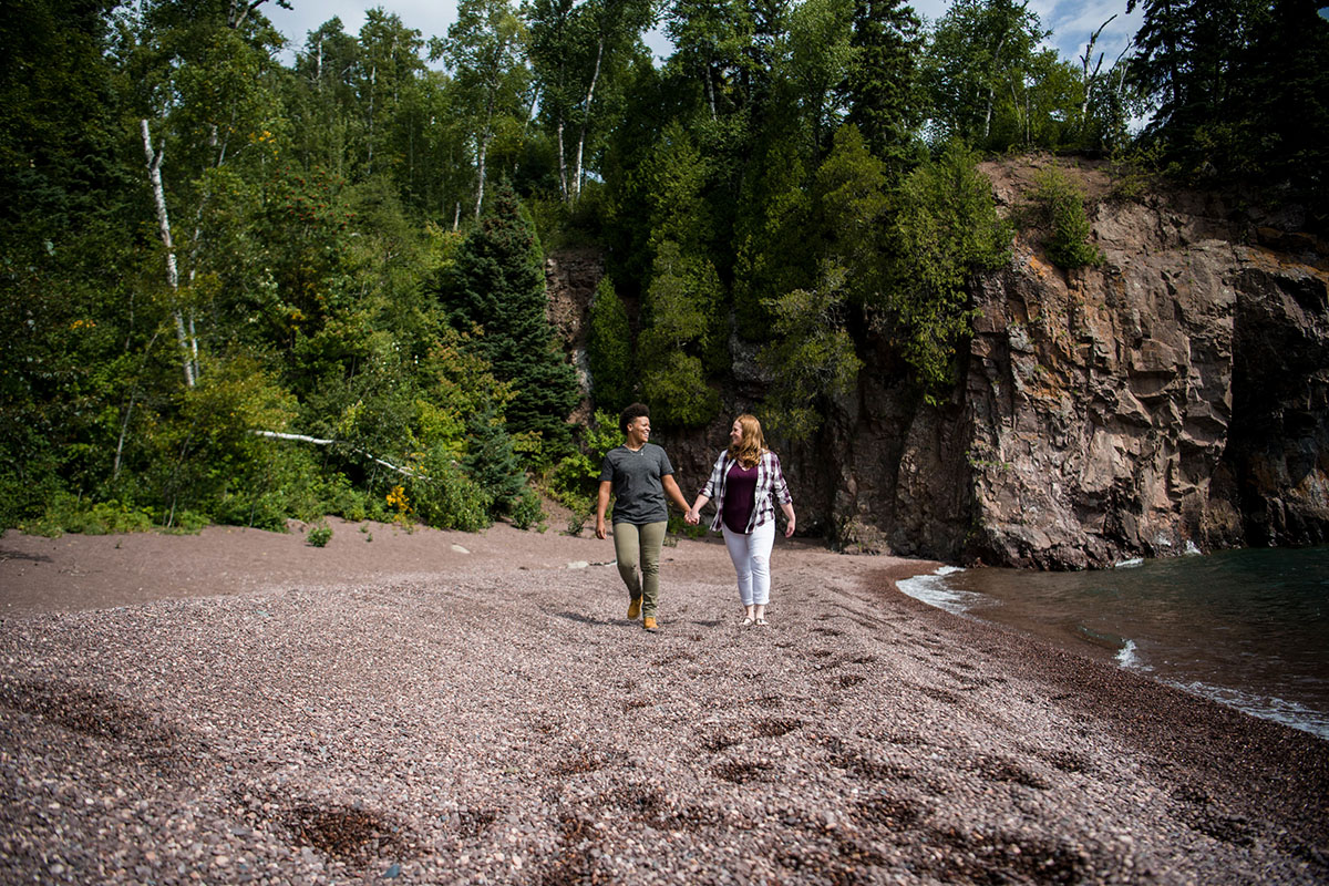 Fun waterfront engagement photos on the coast of Lake Superior holding hands walking