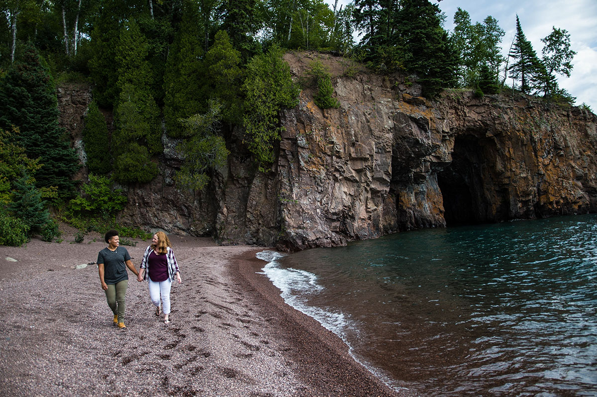 Fun waterfront engagement photos on the coast of Lake Superior holding hands walking