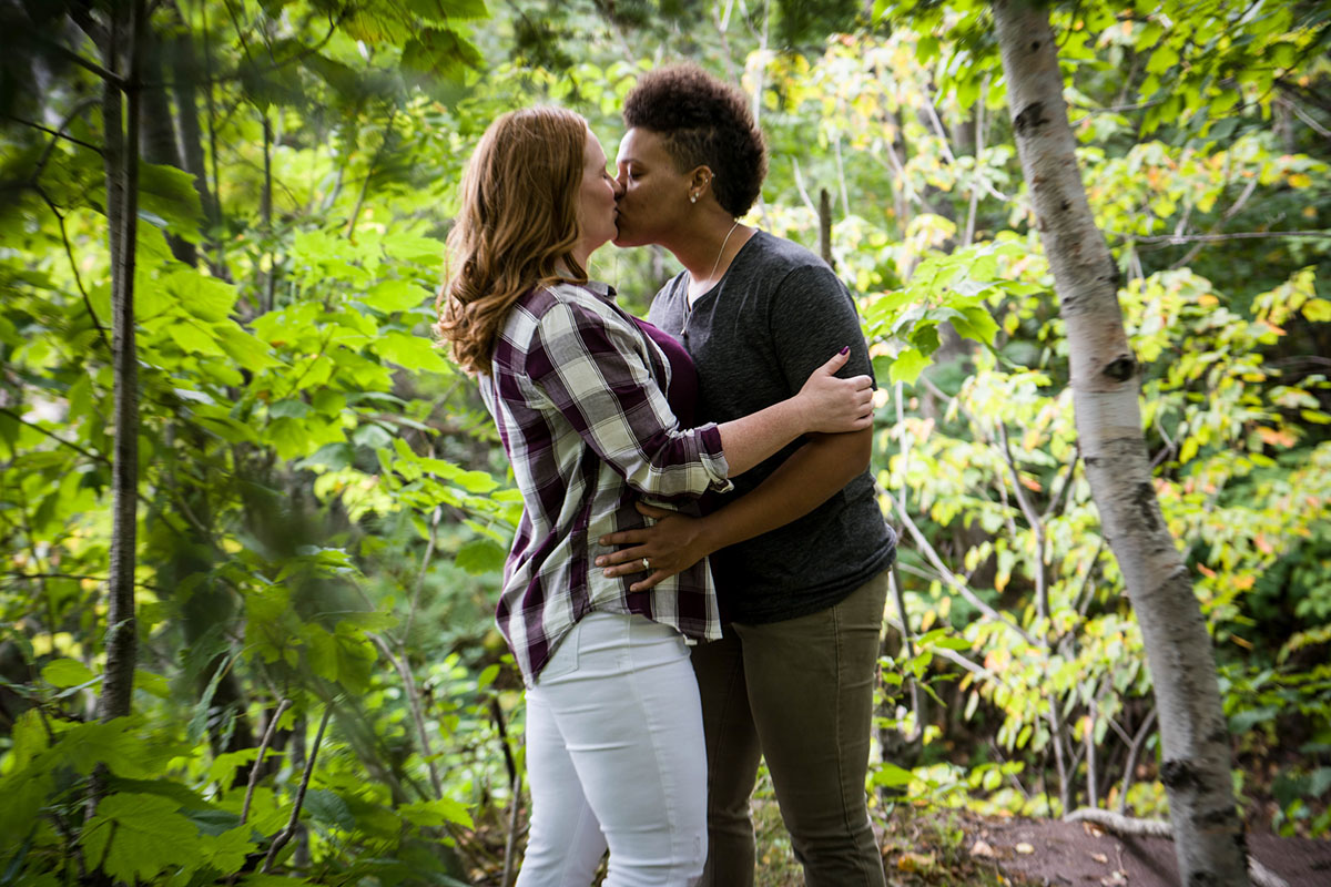 Fun waterfront engagement photos on the coast of Lake Superior kissing trees