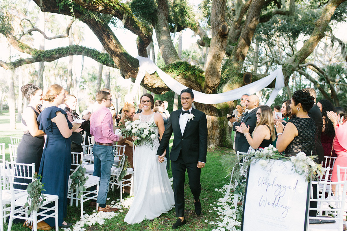 Modern lush greenery wedding in Jacksonville, Florida two brides lace white dress monochrome white roses black tux
