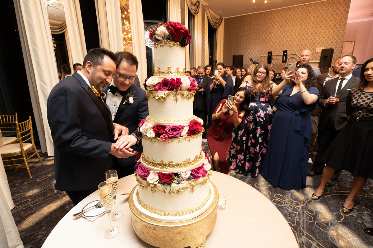 Elegant cathedral wedding in San Francisco, California two grooms black tuxedos cake cutting