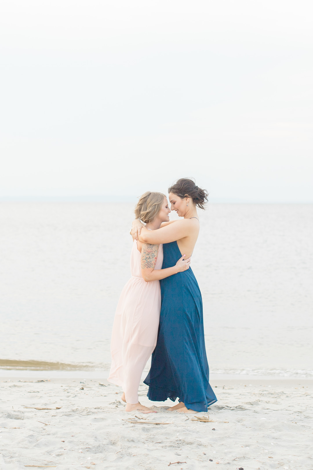 Beach engagement photos at Bayshore Waterfront Park two brides same-sex engagement pink dress blue dress kissing