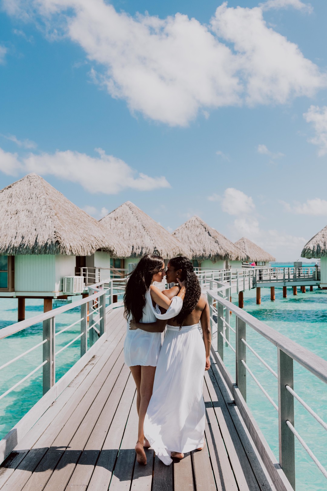 Beach honeymoon photos in Bora Bora two brides white dresses clear blue oceans palm trees