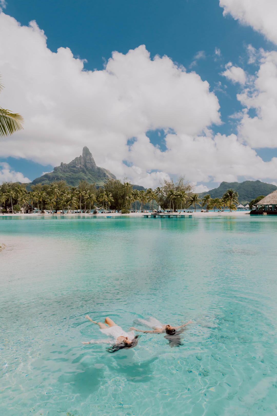 Beach honeymoon photos in Bora Bora two brides white dresses clear blue oceans palm trees swimming