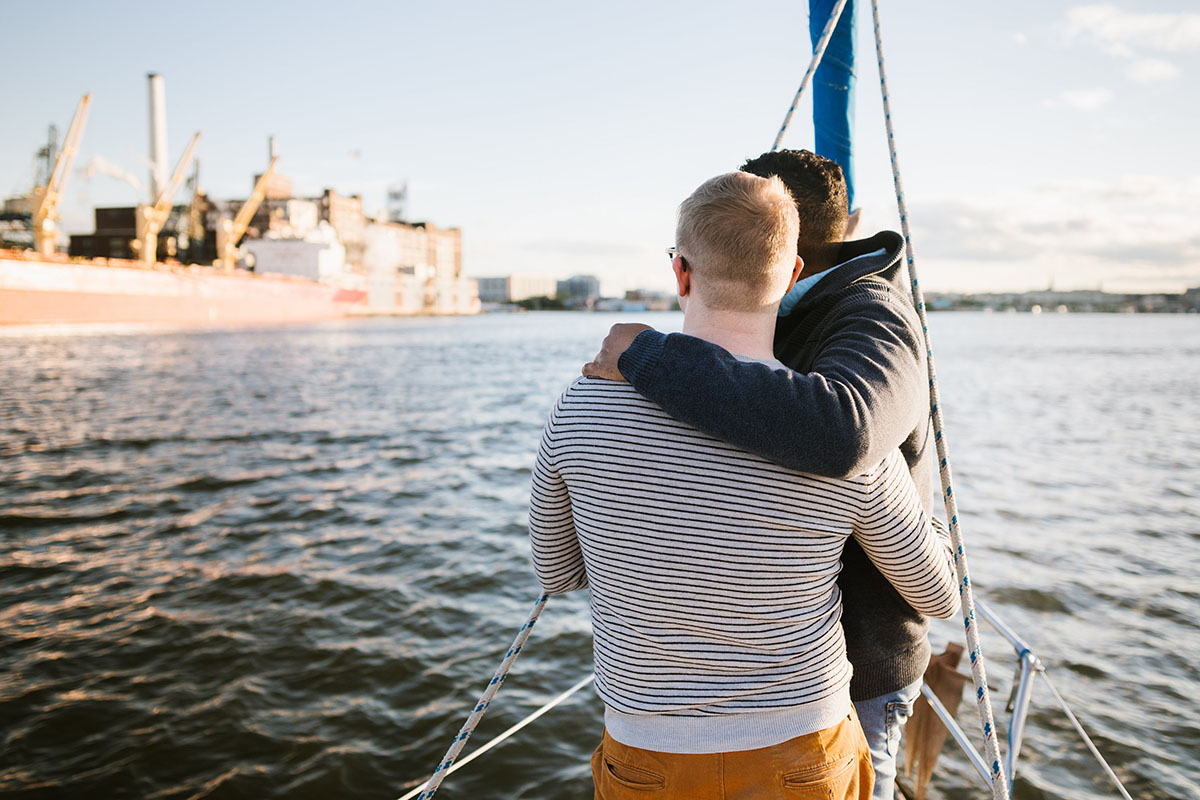 Boat rides and dog walks during loving Baltimore engagement photos two grooms boat water
