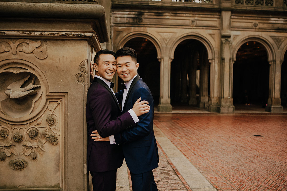 Elegant, fun engagement photos at Central Park with rainbow bubbles two grooms purple tux blue tux bow ties embrace