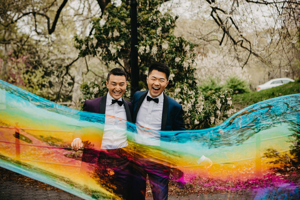 Elegant, fun engagement photos at Central Park with rainbow bubbles two grooms purple tux blue tux bow ties laugh smile
