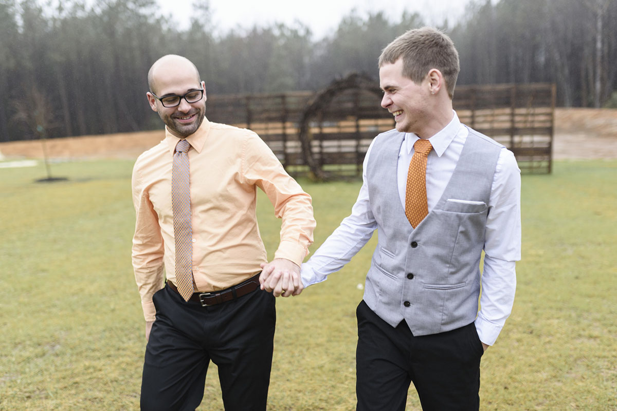 Orange winter elopement inspiration two grooms February wedding holding hands