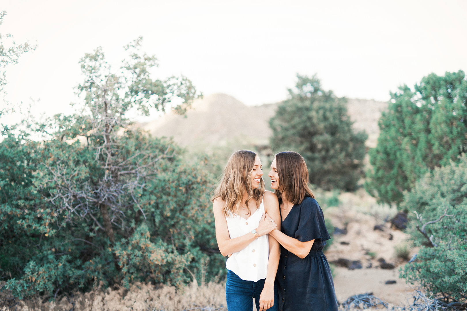 Engagement photos on red rock sandstone cliffs of Snow Canyon LGBTQ+ weddings two brides lesbian engagement Utah