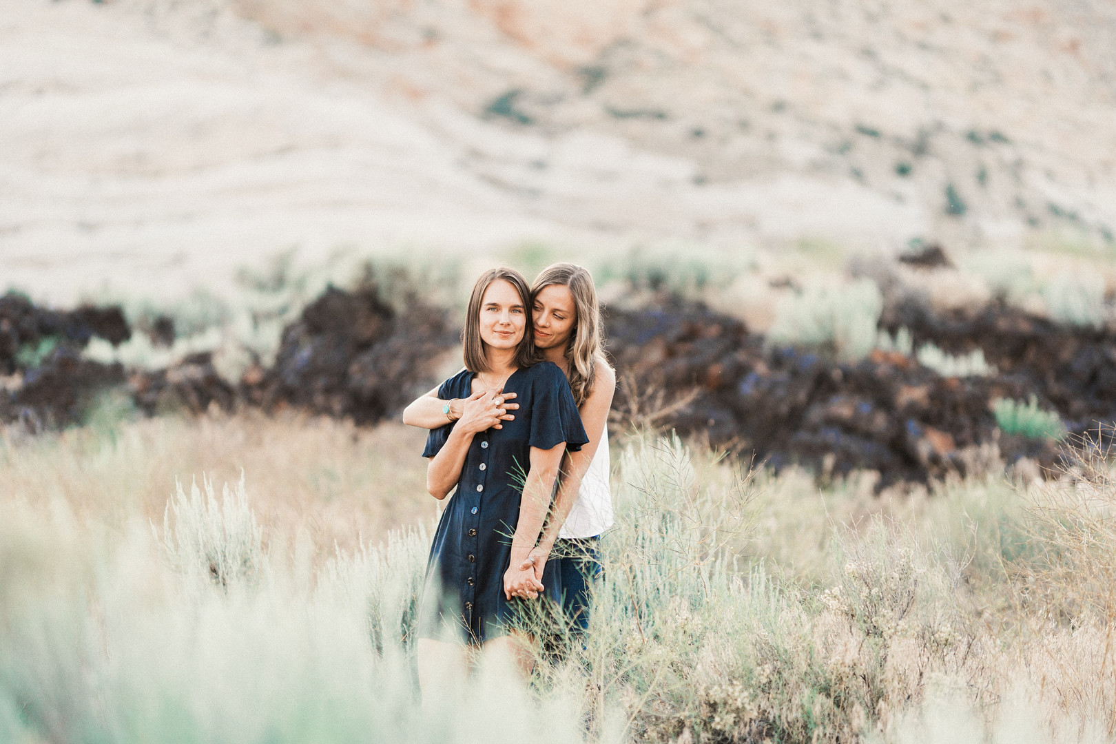 Engagement photos on red rock sandstone cliffs of Snow Canyon LGBTQ+ weddings two brides lesbian engagement Utah