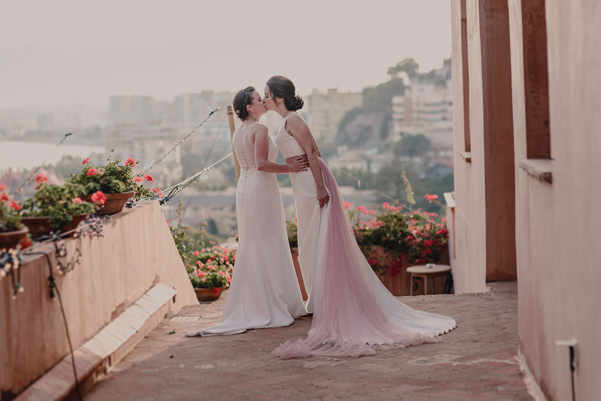 Intimate fall destination wedding at Castillo de Santa Catalina in Spain LGBTQ+ weddings two brides lesbian destination wedding Spanish two white dresses same-sex wedding kiss