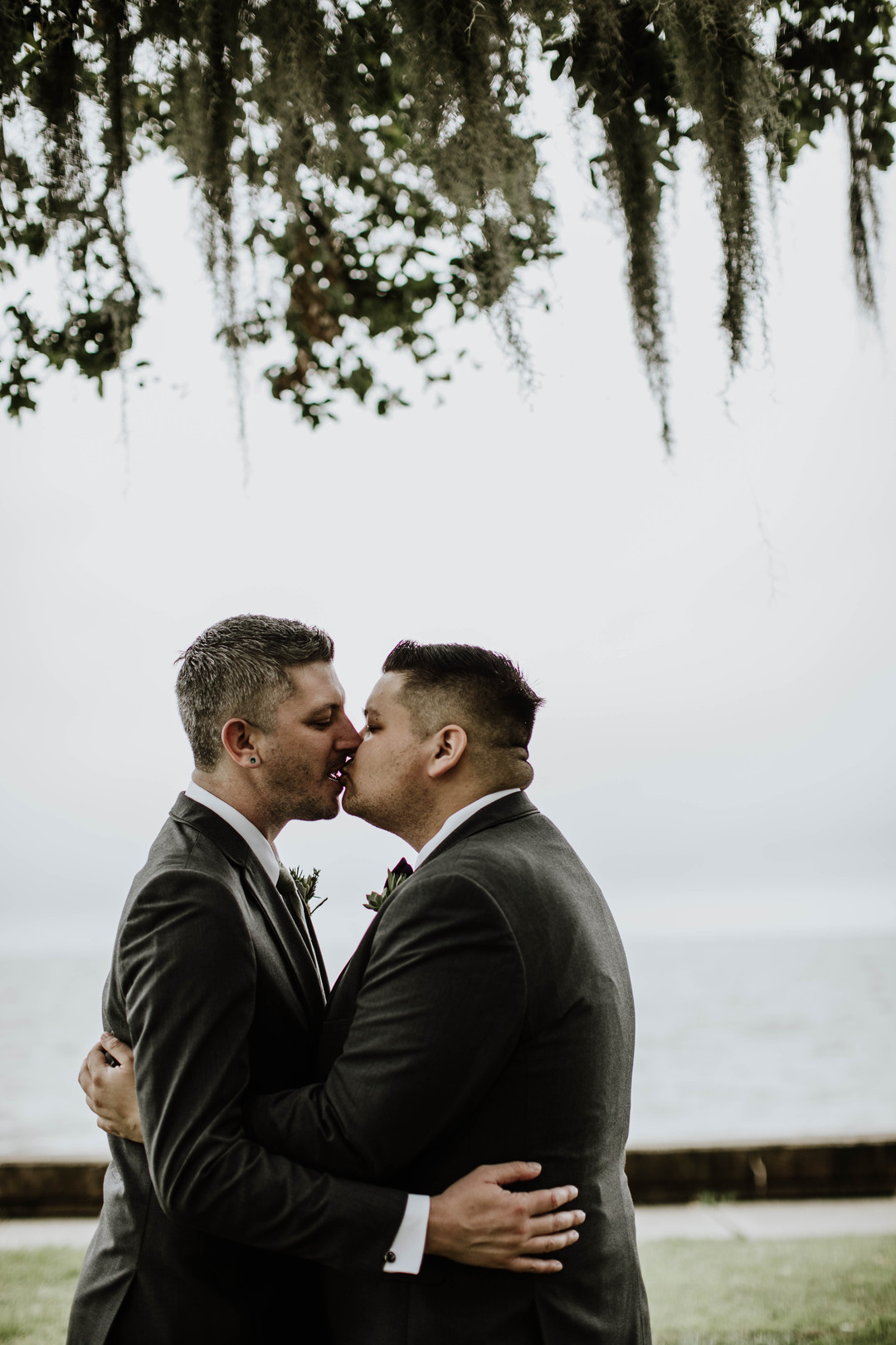 Lakeside historic venue spring wedding in Mandeville, Louisiana two grooms black tuxedos gay wedding kiss
