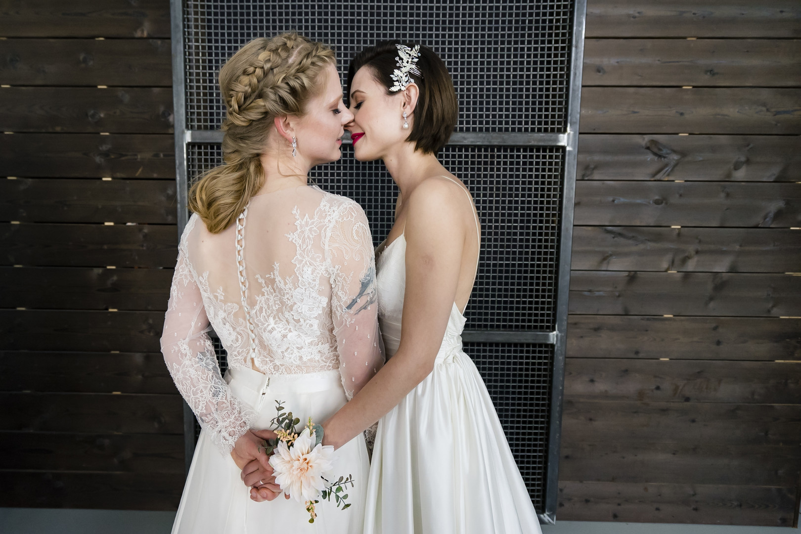 Peach florals warm this industrial distillery wedding inspiration LGBTQ+ weddings same-sex wedding lesbian wedding two brides white dresses kissing tulle