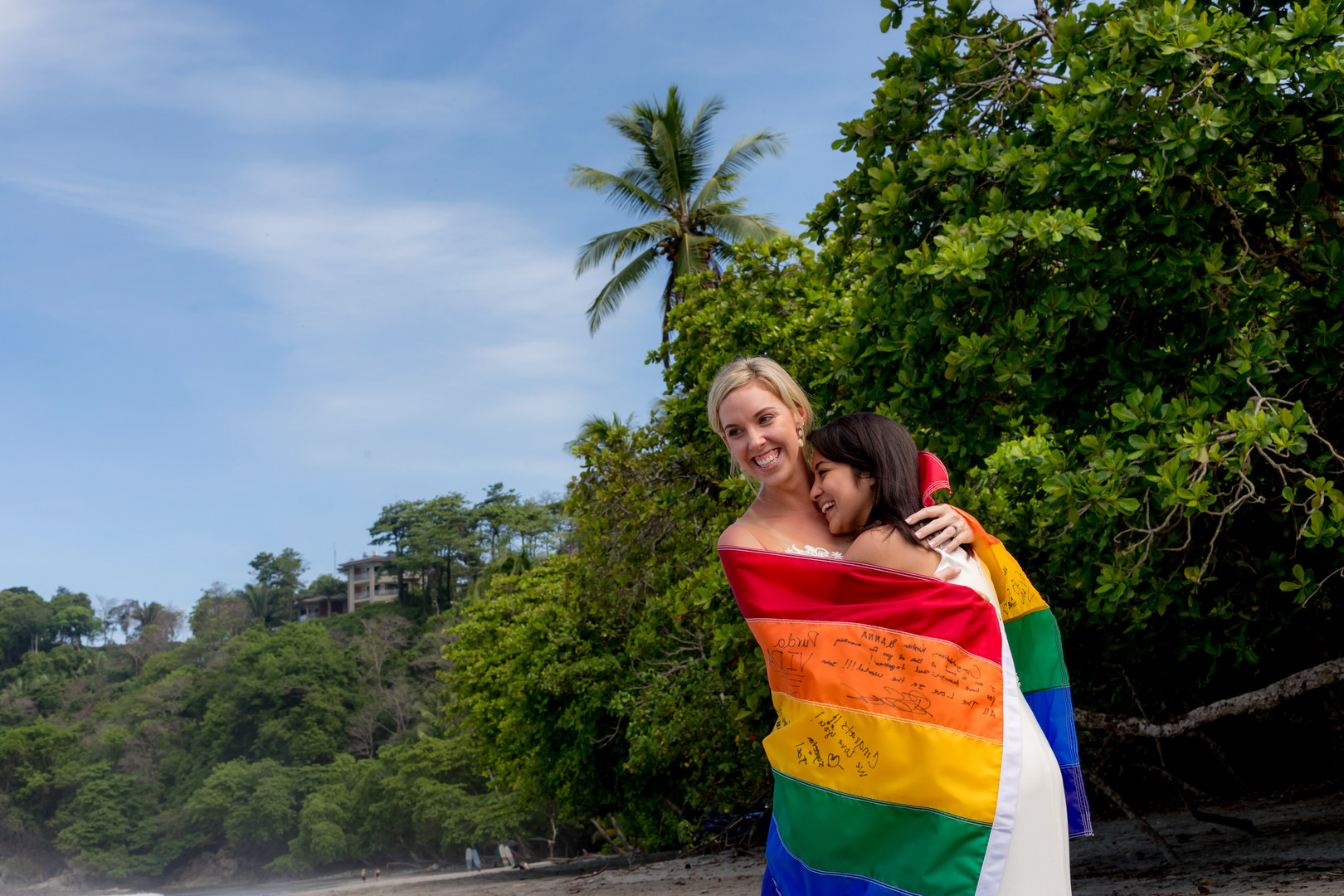 This couple needed a rain plan for their Costa Rica destination wedding LGBTQ+ weddings destination wedding two brides white dresses beach ocean palm tress rainbow flag