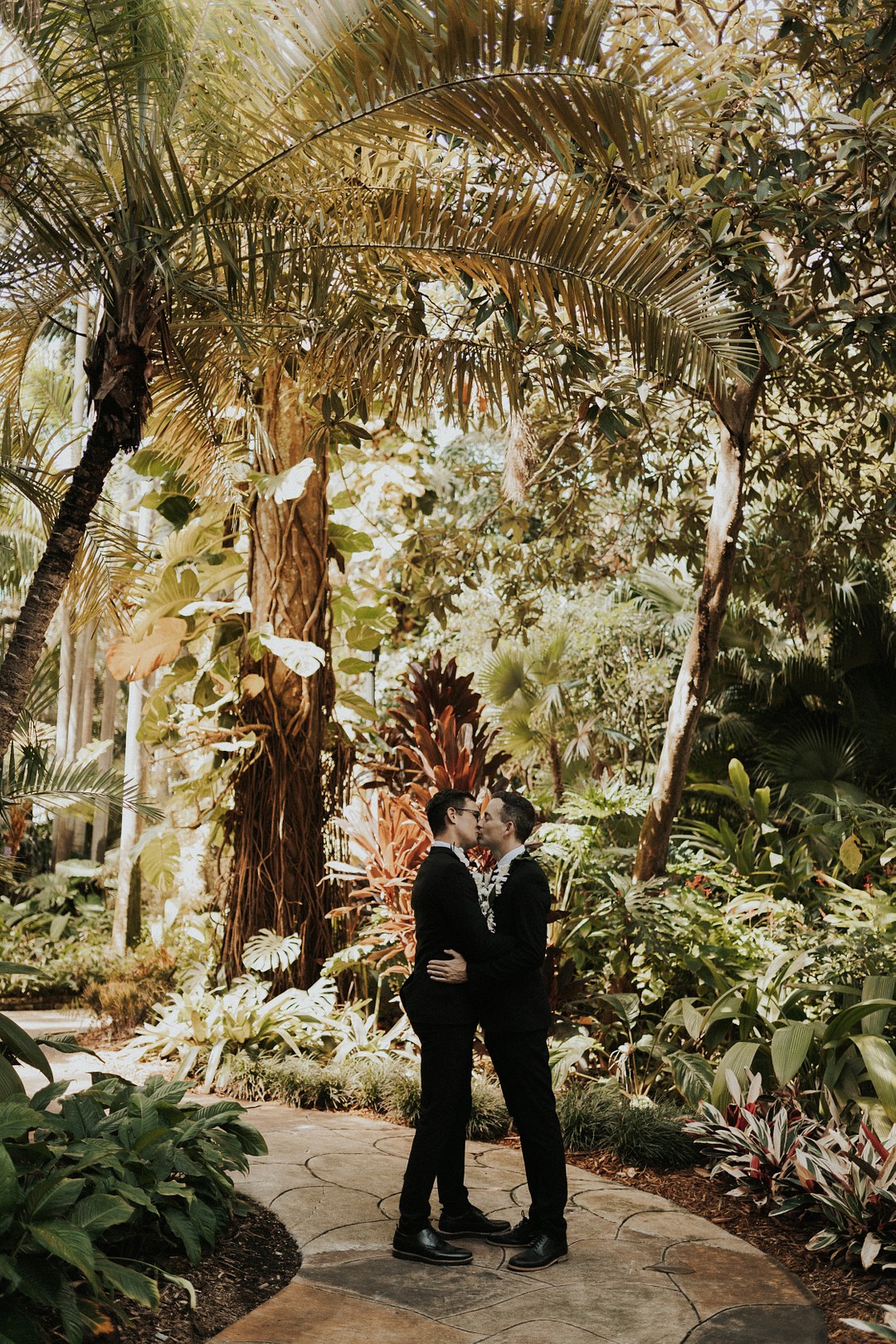 Chic tropical wedding inspiration in Saint Petersburg, Florida LGBTQ+ weddings moody flamingos palm trees Sunken Garden Florida styled shoot two grooms tuxedos leis