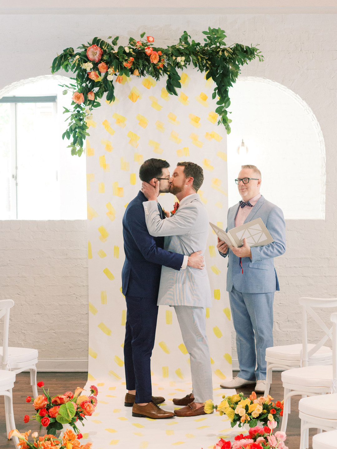 Summer citrus wedding inspiration at historic post office LGBTQ+ weddings two grooms gay wedding blue suit white gray suit orange blue bright colorful summery styled shoot kiss