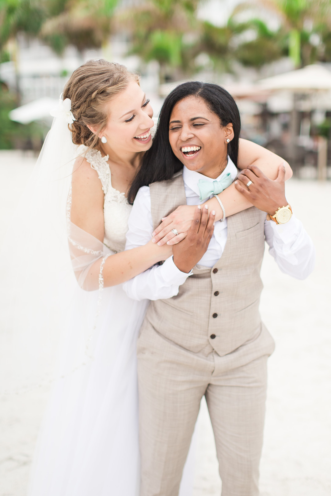 Tropical blue and green beach wedding in St. Petersburg, Florida two brides lesbian wedding white dress tan suit destination LGBTQ+ weddings laugh