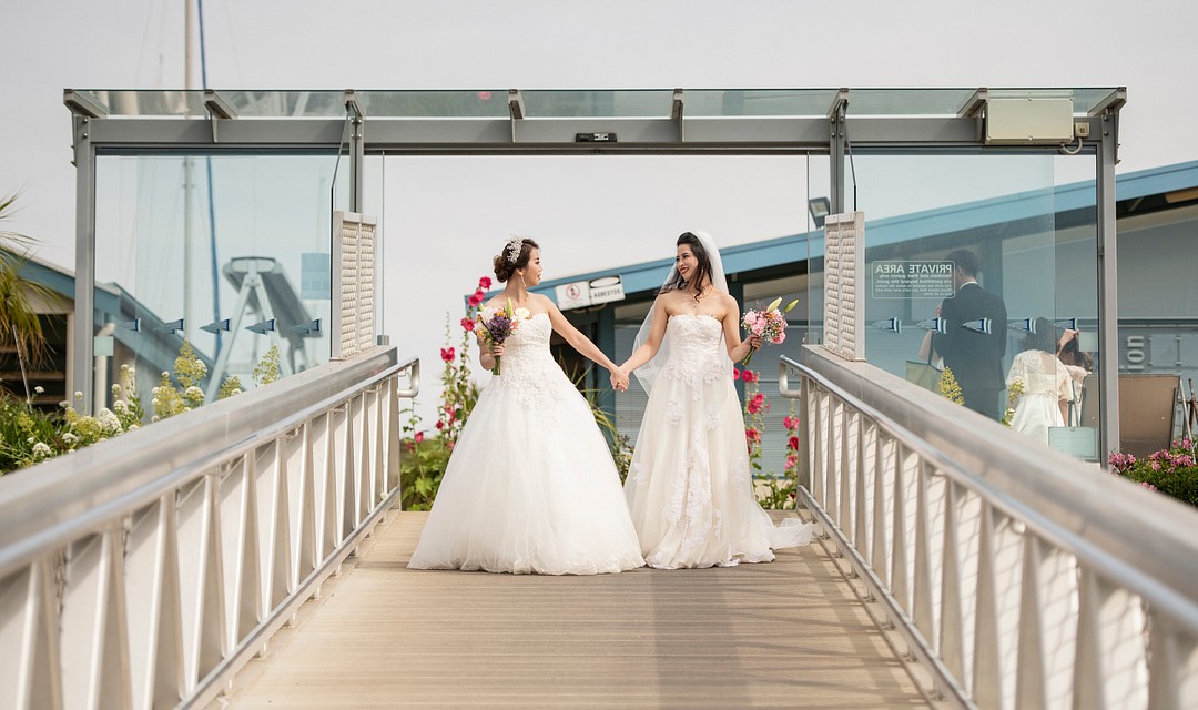 Destination beach yacht club wedding in South Australia LGBTQ+ weddings lesbian wedding two brides Chinese American white dresses docks