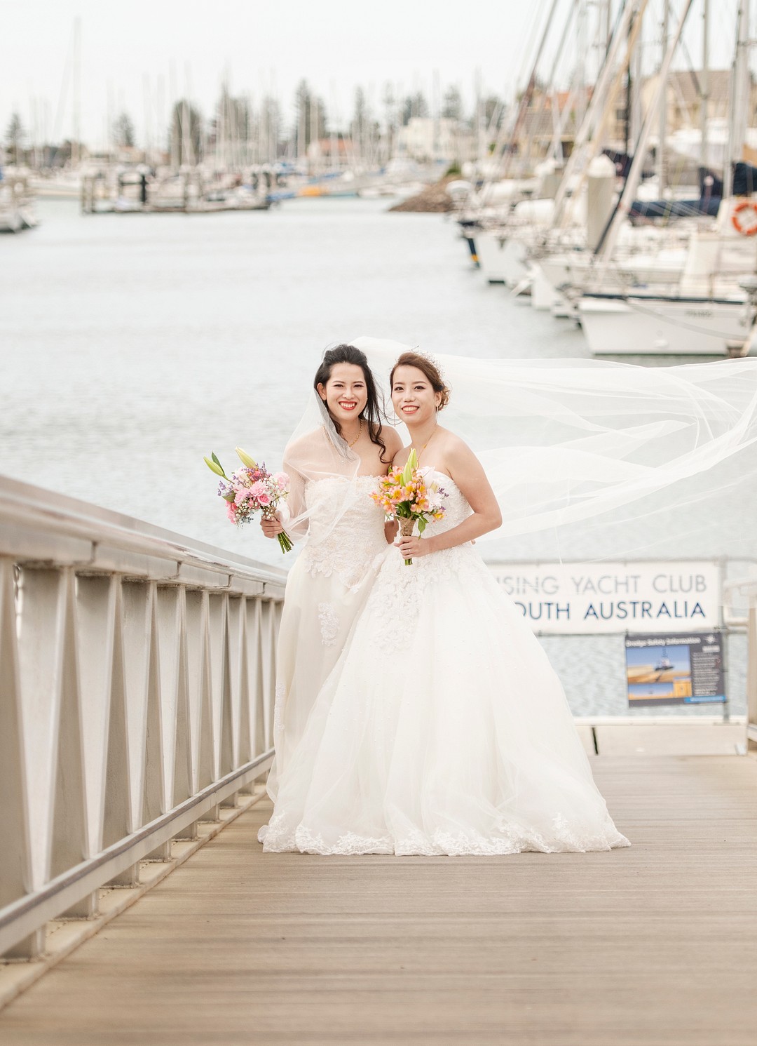 Destination beach yacht club wedding in South Australia LGBTQ+ weddings lesbian wedding two brides Chinese American white dresses docks boats