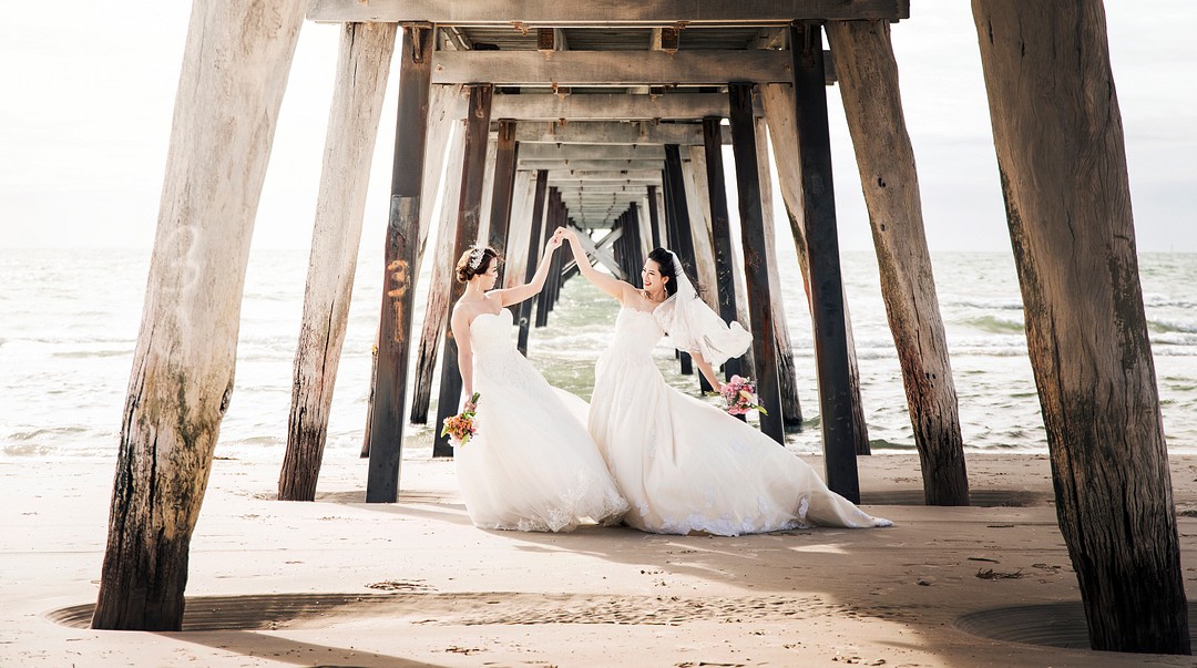 Destination beach yacht club wedding in South Australia LGBTQ+ weddings lesbian wedding two brides Chinese American white dresses pier docks