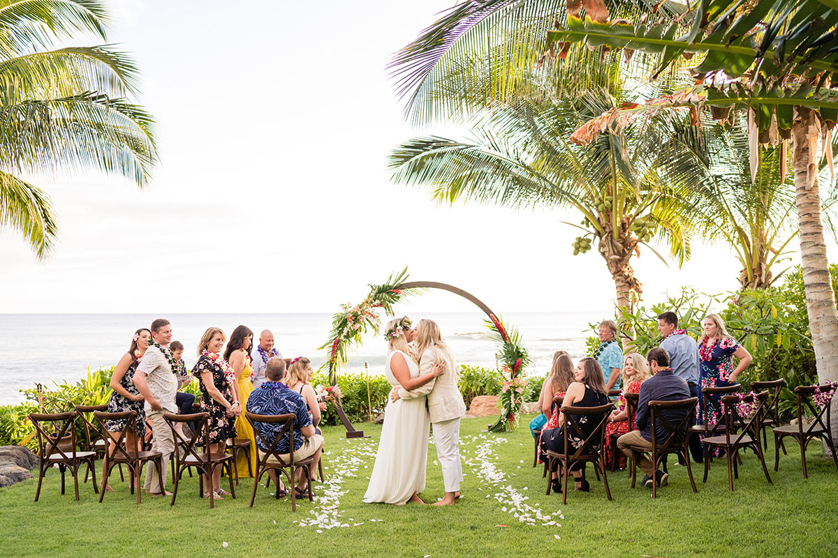 Colorful, floral tropical beach destination wedding in Makaha, Hawaii LGBTQ+ weddings lesbian wedding two brides birds of paradise kiss