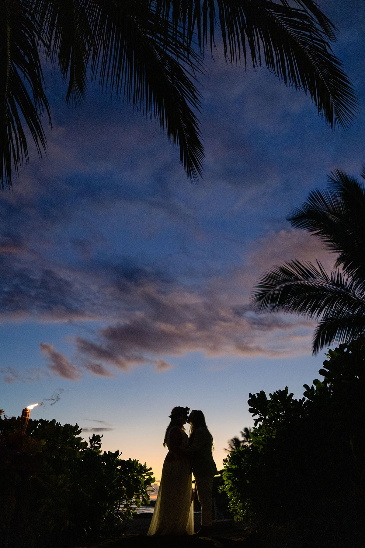 Colorful, floral tropical beach destination wedding in Makaha, Hawaii LGBTQ+ weddings lesbian wedding two brides birds of paradise night sky