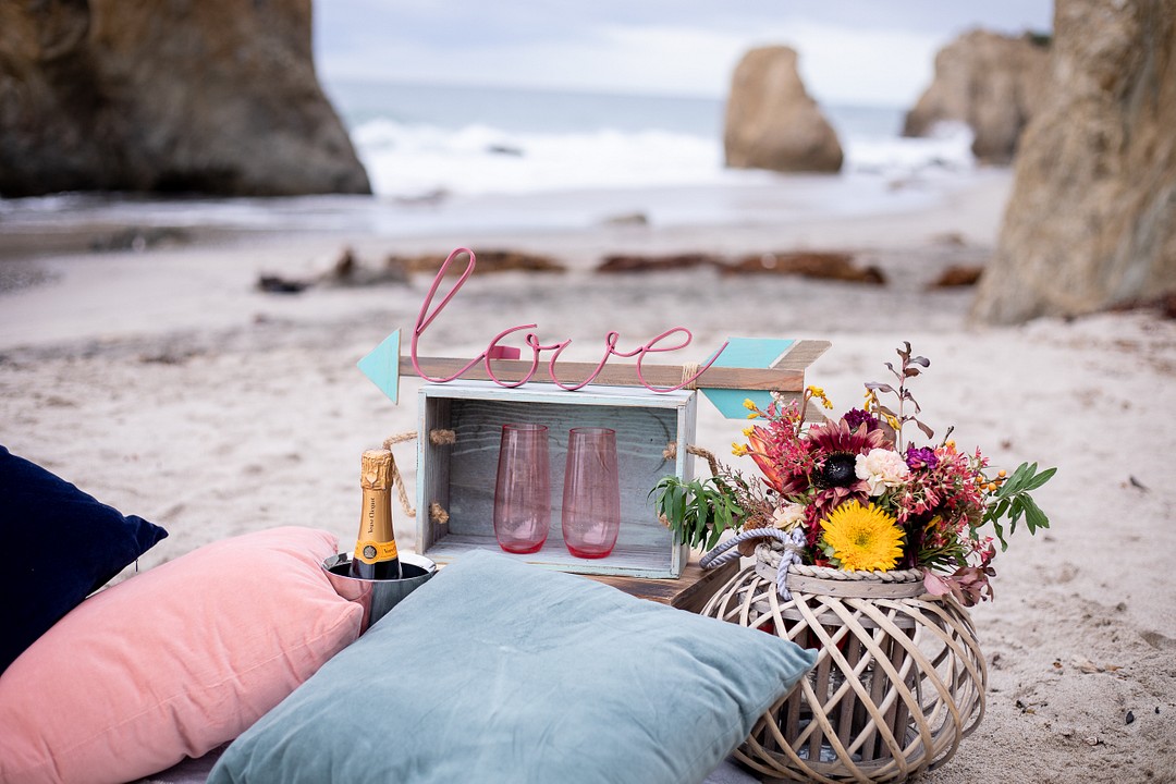 Cliffside fall El Matador Beach proposal with romantic picnic LGBTQ+ engagements weddings proposals surprise California Malibu two brides