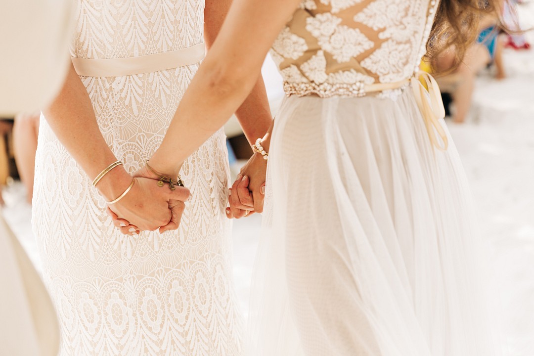 Carefree bohemian beach wedding in Pensacola, Florida LGBTQ+ weddings two brides holding hands
