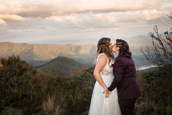 Fall golden hour mountain elopement with dog attendants LGBTQ+ weddings mountaintop queer wedding same-sex wedding burgundy tux white lace dress intimate small kiss