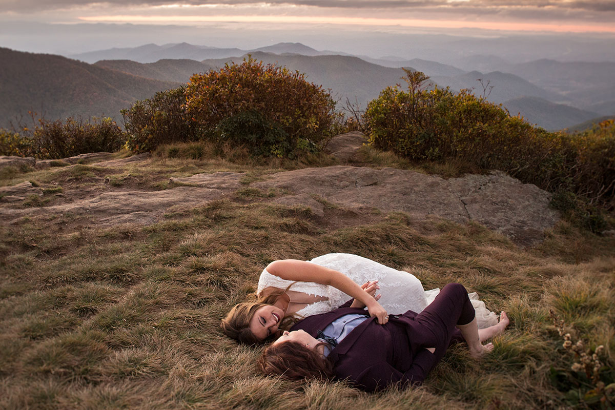 Fall golden hour mountain elopement with dog attendants LGBTQ+ weddings mountaintop queer wedding same-sex wedding burgundy tux white lace dress intimate small laying down