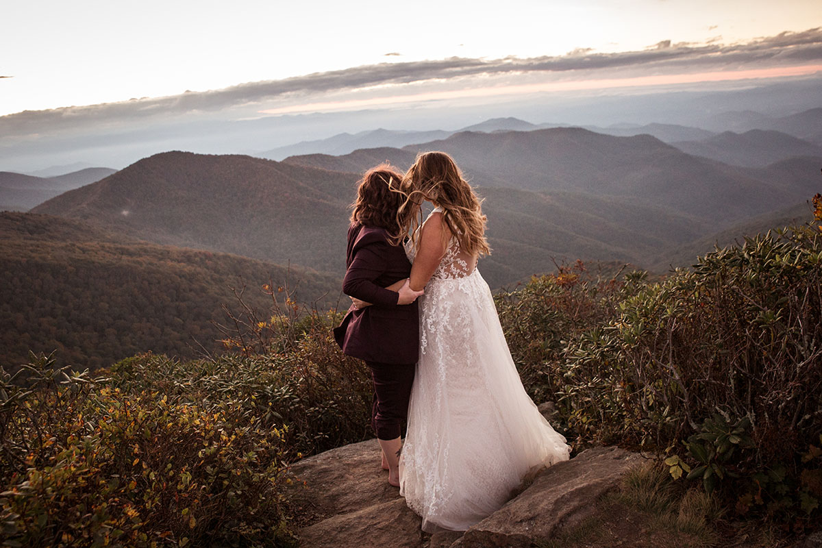 Fall golden hour mountain elopement with dog attendants LGBTQ+ weddings mountaintop queer wedding same-sex wedding burgundy tux white lace dress intimate small