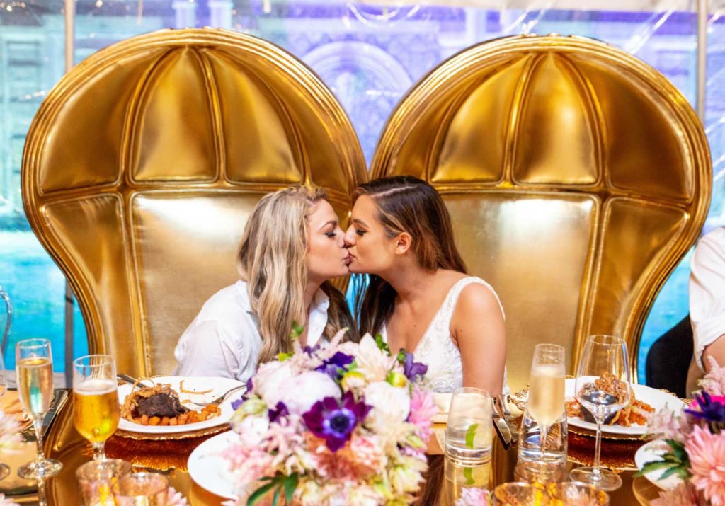 Angelina + Krista: Upscale glamorous lesbian wedding at the renowned Versace mansion in Miami Beach, Florida Suzanne Delawar Studios newlywed brides kiss in opulent gold chairs