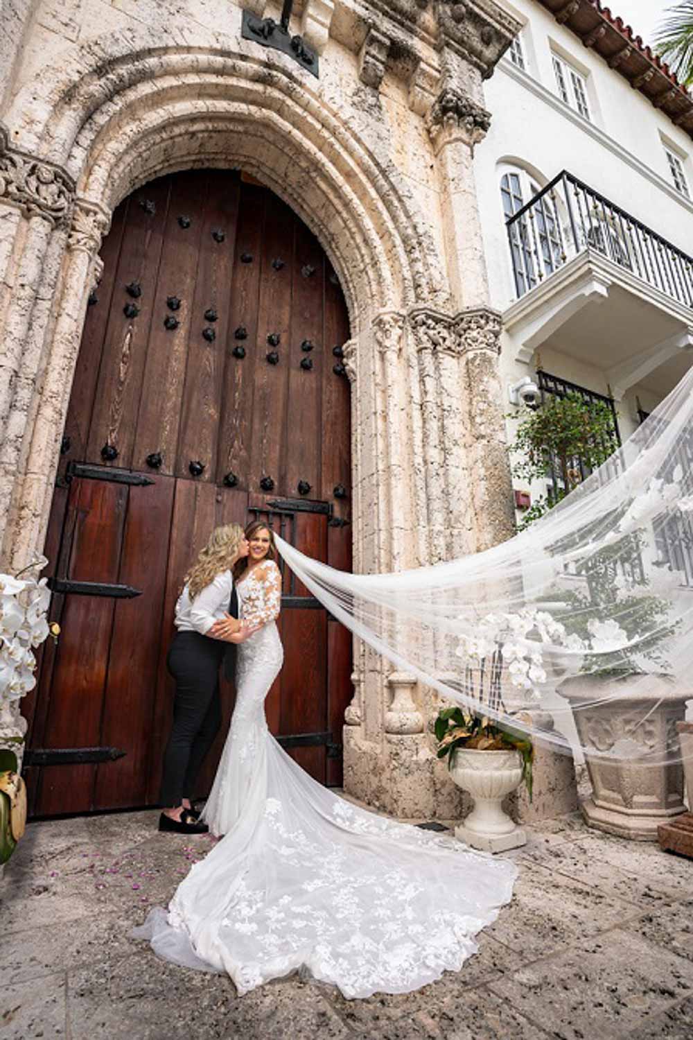 Angelina + Krista: Upscale glamorous lesbian wedding at the renowned Versace mansion in Miami Beach, Florida Suzanne Delawar Studios brides veil in the wind