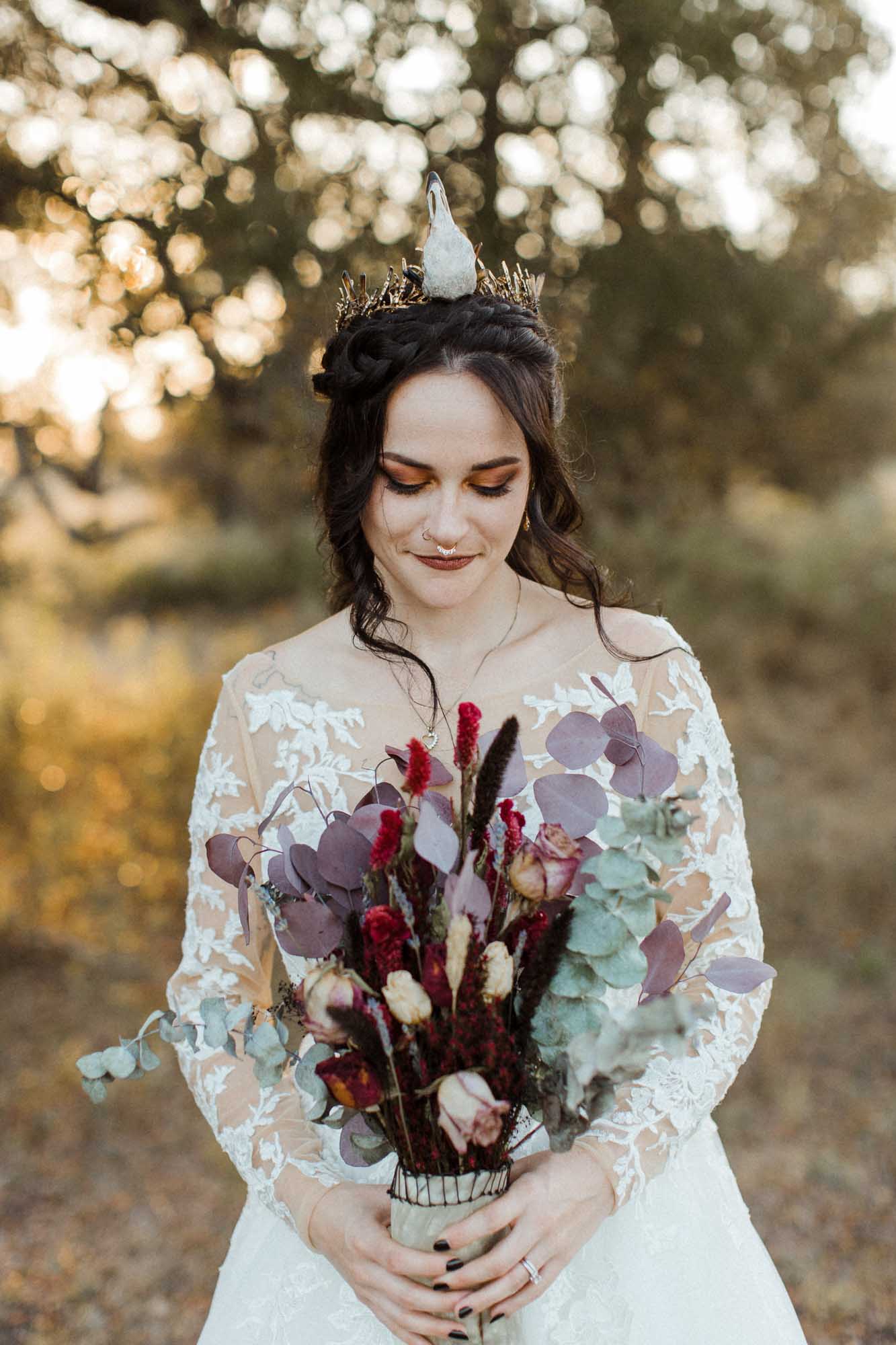 Beautifully gothic Texas wedding with creative details, photo by Leah Thomason Photography, featured on Equally Wed, the LGBTQ+ wedding magazine bride in bird skull bridal crown and lace wedding gown holding bouquet in animal horn