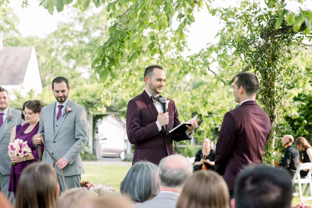 LGBTQ+ wedding featured on Equally Wed magazine with two grooms Brian + Brett: Hudson Valley garden wedding with shades of purple Upasana Mainali Photography reading vows in wedding ceremony