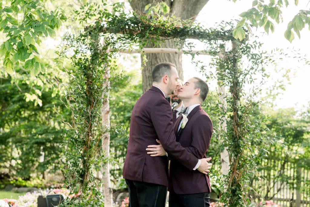 LGBTQ+ wedding featured on Equally Wed magazine with two grooms Brian + Brett: Hudson Valley garden wedding with shades of purple Upasana Mainali Photography wedding ceremony kiss